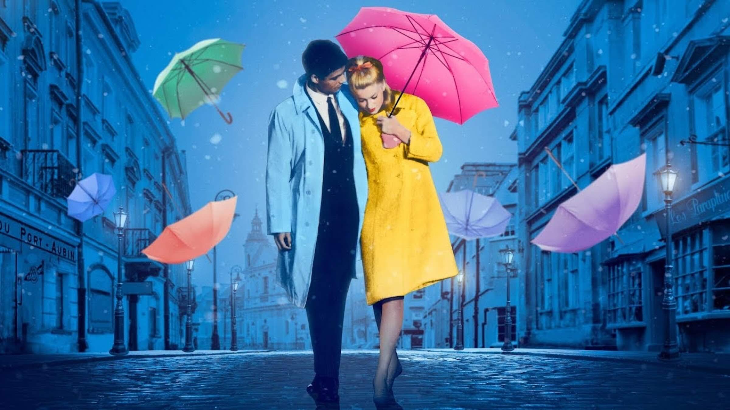 Geneviève Émery (Catherine Deneuve) and Guy Foucher (Nino Castelnuovo) walking together under an umbrella in 'The Umbrellas of Cherbourg,' 10 Most Beautiful Movies of All Time