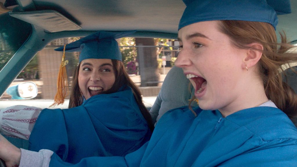 Amy (Kaitlyn Dever) and Molly (Beanie Feldstein) is blue caps and gowns driving frantically to graduation in 'Booksmart'