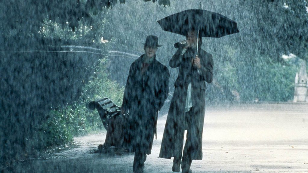 Withnail (Richard E. Grant) and "...& I"/Marwood (Paul McGann) walking in the rain.