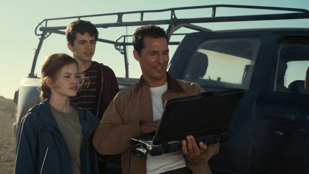 Cooper (Matthew McConaughey) and his children look at a laptop in a cornfield. 